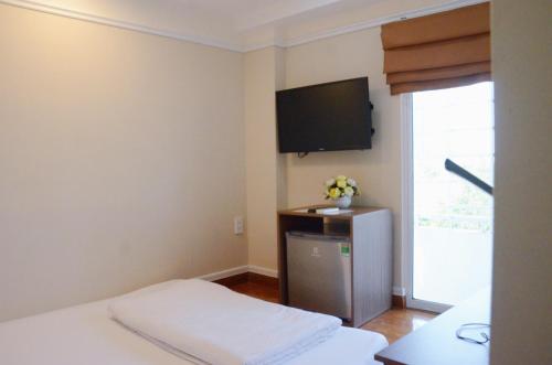 a room with a bed and a tv on the wall at Good For You Hotel in Ho Chi Minh City