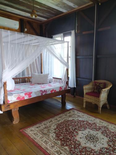 a bedroom with a bed with a canopy and a rug at Rock and Wreck Dive Resort in Tanjungbinga