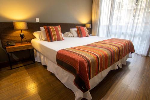 a hotel room with a large bed with a striped blanket at Cozy Studio Palermo Soho -T211- in Buenos Aires
