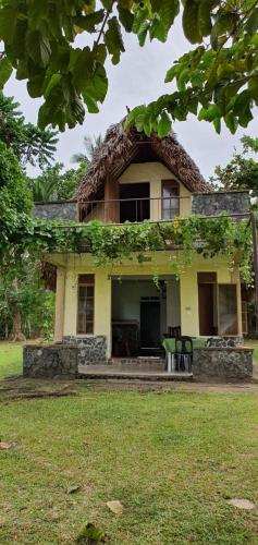 a yellow house with a thatched roof at Viento de Mar in Gindi