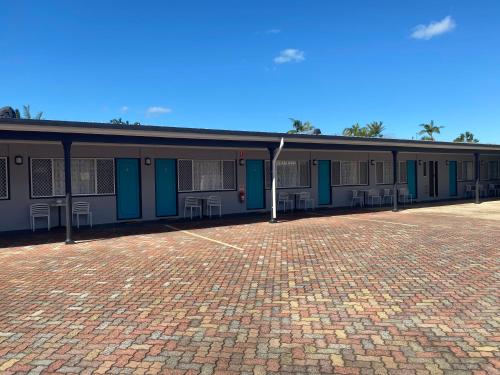a building with blue doors and a brick driveway at Hervey Bay Motel in Hervey Bay