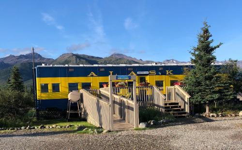 a yellow and blue train car with mountains in the background at Denali Park Hotel in Healy