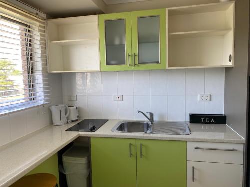 a kitchen with green cabinets and a sink at Hervey Bay Motel in Hervey Bay