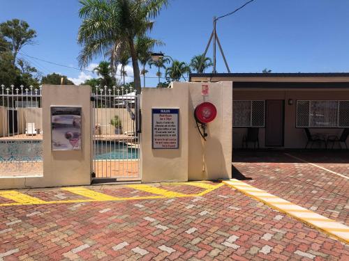 a gate with a pool and a sign in front of a fence at Hervey Bay Motel in Hervey Bay