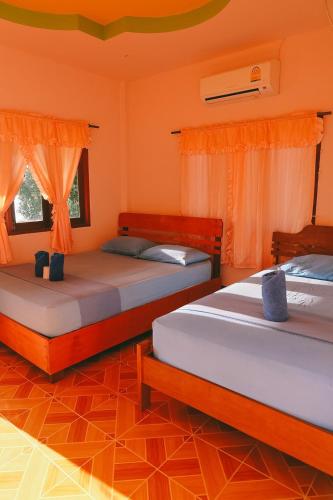 two beds in a room with orange walls at J.B.Hut Bungalows in Haad Yao