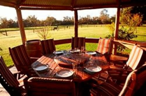 een houten tafel met stoelen eromheen op een veranda bij Lazy River Boutique Bed & Breakfast in Pinjarra