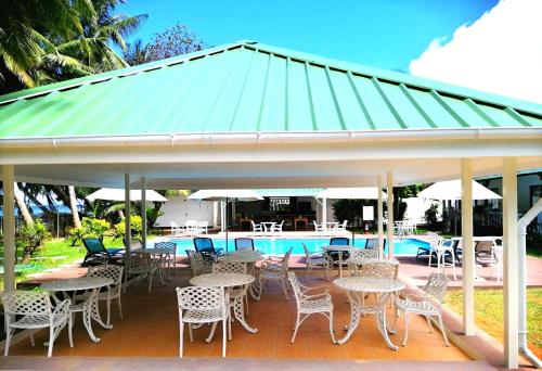 a pavilion with tables and chairs next to a pool at Le Relax Beach Resort in Grand'Anse Praslin
