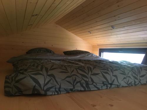 Cama en habitación con techo de madera en Tiny House Otra Cosa en Mouscron