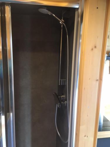 a shower in a glass door with a shower head at Tiny House Otra Cosa in Mouscron