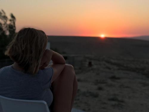 a woman sitting in a chair watching the sunset at Sun, Mountain & Adventure in Arad