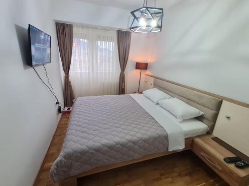 a small bedroom with a bed and a television at Astra Apartments Skopje in Skopje