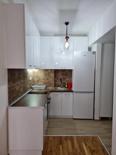 a kitchen with white cabinets and a refrigerator at Astra Apartments Skopje in Skopje