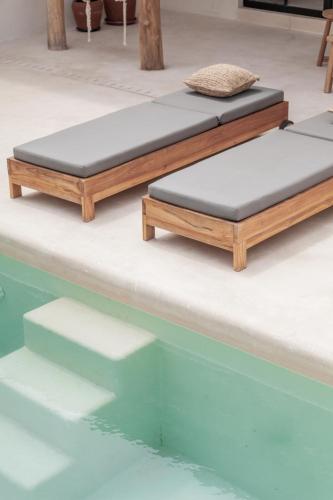 two beds sitting next to a swimming pool at YUCCA villas in Canggu
