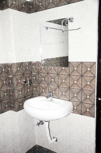a white sink in a bathroom with tiles at Ishaan Hotel in Gangānagar