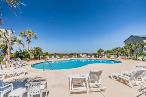 a pool with white chairs and palm trees at Harbor Island M118 in Oceanmarsh Subdivision