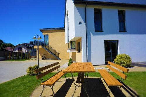 a picnic table and benches in front of a building at Smėlio Vila Apartments in Palanga