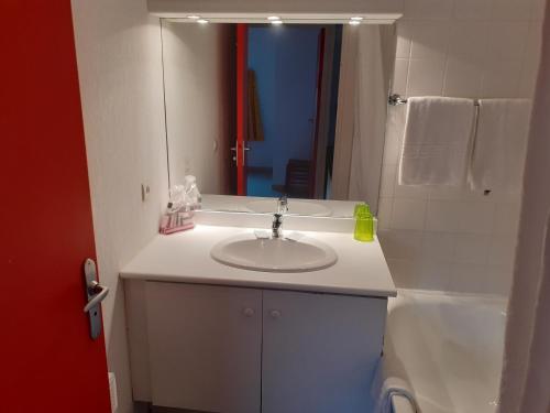 a white bathroom with a sink and a mirror at Gîte du Gua des Brasses au bord du lac de la Raviège in La Salvetat