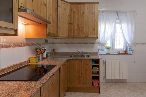 a kitchen with wooden cabinets and a sink at Casa entre "Mar y Montaña" centro de Cantabria, terraza, ajardinada, amplia y luminosa, hasta 10 personas in Puente San Miguel
