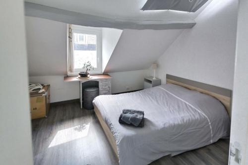 een slaapkamer met een wit bed met een zwart kussen erop bij LE KALEHO, Grand Duplex au coeur de Dieppe - NETFLIX in Dieppe