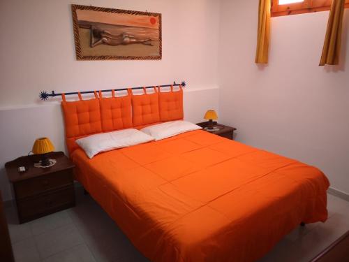 an orange bed in a room with two night stands at Casa Adriana in Alghero