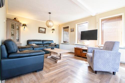 a living room with leather furniture and a flat screen tv at Hotel het Rietershuijs in Kalenberg