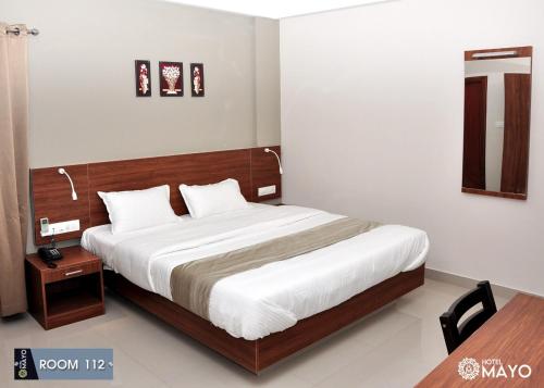 1 dormitorio con 1 cama grande y cabecero de madera en Hotel Mayo, en Wayanad