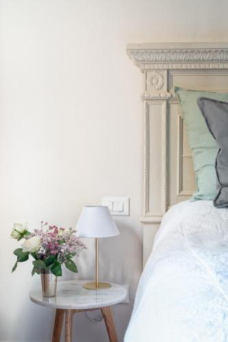 a white bedroom with a bed and a table with a lamp at Villa La Petraia in Panzano
