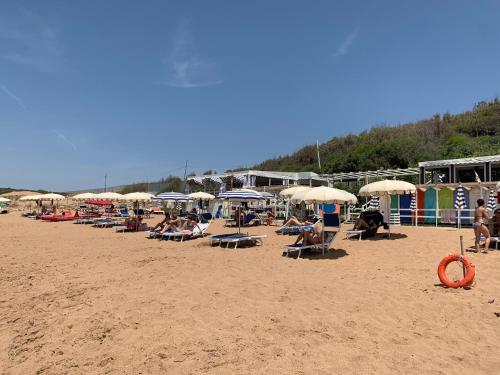 a group of people sitting on a beach with umbrellas at La Rosa Hotel - Selinunte in Marinella di Selinunte