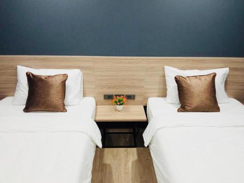 two beds with pillows and a table in a room at Oblique Apartment - ออฟบลิค อพาร์ทเมนท์ in Nonthaburi