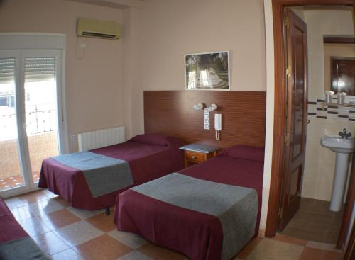 a hotel room with two beds and a sink at Hostal Alamare in Seville