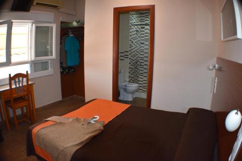 a bedroom with a bed and a bathroom with a toilet at Hostal Alamare in Seville
