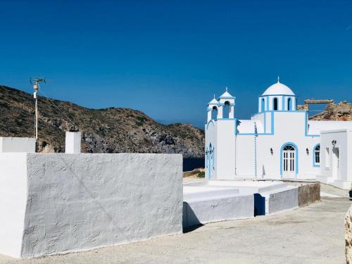 a white church with a hill in the background at Salty Kisses and Sandy Toes in Firopótamos