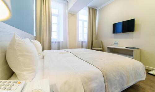 1 dormitorio con 1 cama blanca grande y TV en ROSSI HOTEL, en Tver