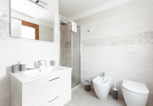 a white bathroom with a sink and a toilet at Hotel Residence - Il Giardino del Cigno in Latisana