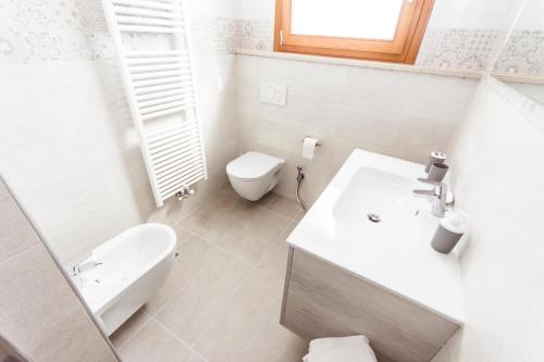a white bathroom with a toilet and a sink at Hotel Residence - Il Giardino del Cigno in Latisana
