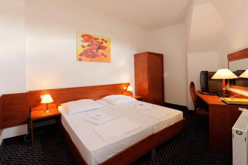 a bedroom with a bed and a desk and a television at City Hotel am Kurfürstendamm in Berlin
