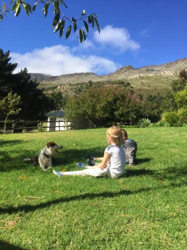 two children and a dog sitting in the grass at High Season Farm Luxury Cottages in Hermanus