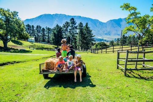 a group of children sitting on a trailer in a field at High Season Farm Luxury Cottages in Hermanus