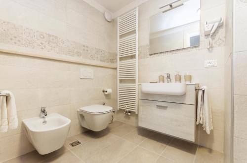 a white bathroom with a sink and a toilet at Hotel Residence - Il Giardino del Cigno in Latisana