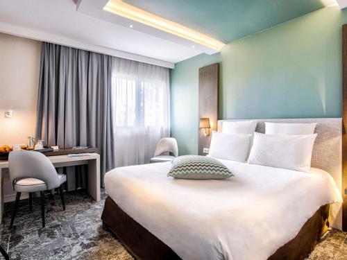 a hotel room with a large bed and a large window at Mercure Cabourg Hôtel & Spa in Cabourg