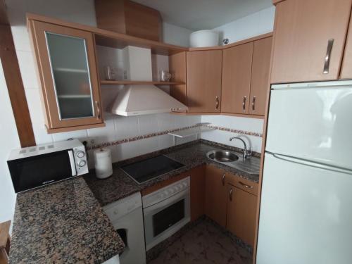 a kitchen with a white refrigerator and a sink at Apartamento Conil Zona tranquila con fácil aparcamiento in Conil de la Frontera