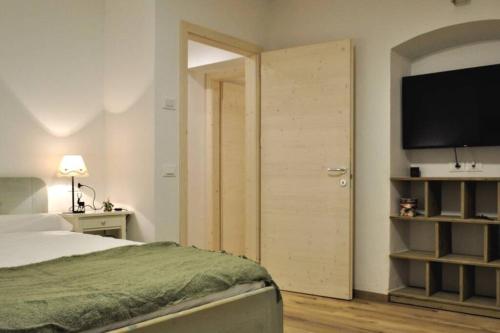 a bedroom with a bed and a flat screen tv at Appartamento Dolomella in Fai della Paganella