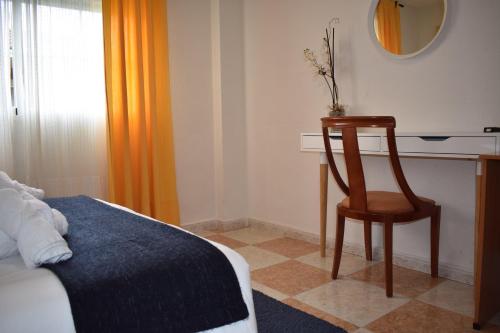 a bedroom with a bed and a chair next to a desk at Hotel El Ancla in Villanueva de la Cañada