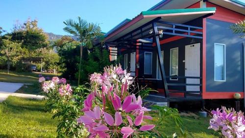 een klein huis met roze bloemen ervoor bij โคโค่เขาค้อรีสอร์ท in Campson