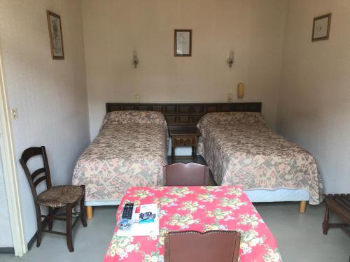 two beds in a small room with a table and a table sidx sidx at Hébergements à La Rive, Accueil ouvert tous les jours jusqu'à 20h00 dernier délai, depuis 30 ans ! Réserver ici svp ! Merci ! Aucun règlement à distance accepté, Paiement par CB, Espèces, Chèque ou Chèques-Vacances impérativement à la remise des clefs ! in Amélie-les-Bains-Palalda