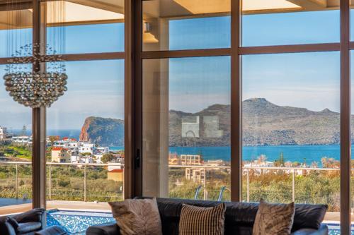 een woonkamer met een bank en grote ramen bij Luxury 6-Bedroom Villa With Private Pool- Villa Prigipessa in Chania