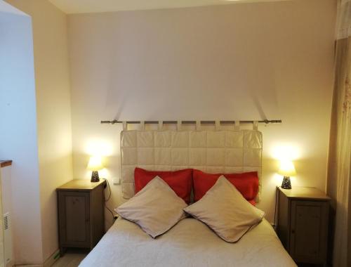 ein Schlafzimmer mit einem Bett mit roten Kissen und zwei Lampen in der Unterkunft Gite des Gorges de l'Ardèche in Chame