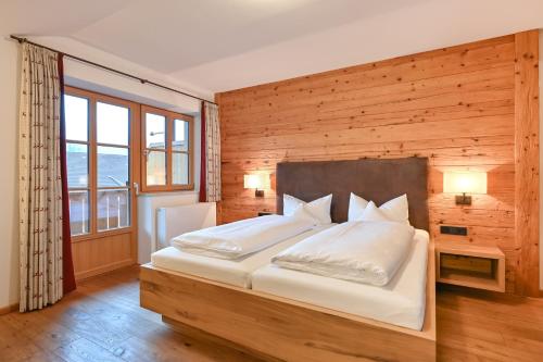 a bedroom with a large bed with a wooden wall at Hotel Helmer in Schwangau