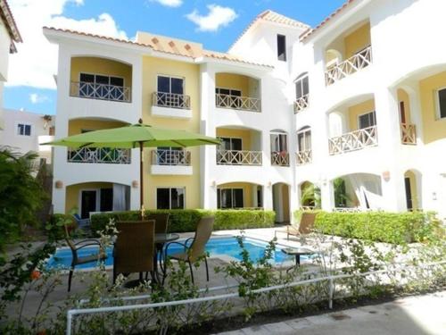 a large white building with a pool and an umbrella at Casa Vacanze Paola in Bayahibe