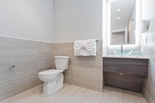 a bathroom with a toilet and a sink and a mirror at Sunset Caribe Belize in San Pedro